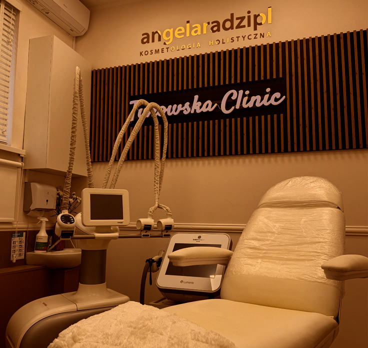 Gabinet kosmetyczny z fotelem zabiegowym i sprzętem medycznym, logo kliniki na ścianie.